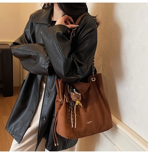 Détail d'un sac cabas en daim marron avec bandoulière chaîne et breloque ourson