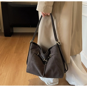Detail of dark brown tote bag featuring matte texture and golden metallic buckle