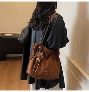 Détail du sac cabas en daim marron avec pendentif ours et bandoulière chaîne sur modèle