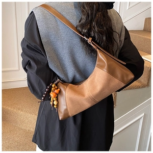 Détail d'un sac à bandoulière vintage en cuir patchwork marron avec breloque en perles