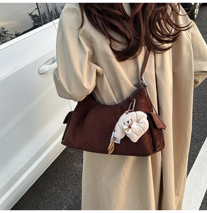 Détail du sac croissant en daim marron foncé avec un charmant chien en peluche sur un trench