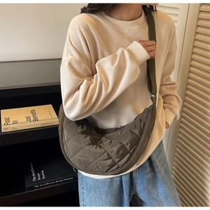 Quilted olive green half-moon crossbody bag with adjustable wide strap shown on model