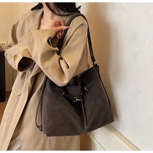 Detail of dark brown vintage leather tote bag with gold metal buckle and textured finish
