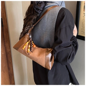 Gros plan sur le sac vintage marron avec patchwork en daim et pompon en perles de bois