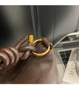 Detail of matte gold hardware and knotted leather handle on vintage brown handbag