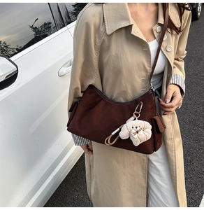 Détail du sac à main en daim marron foncé avec pendentif chien en peluche et design plissé