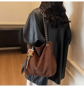 Détail du sac cabas en daim marron café avec chaîne en métal et breloque ours
