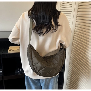 Detail of olive green quilted hobo bag with nylon texture and wide strap on shoulder