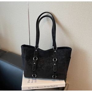 Detail of vintage black tote bag with dual shoulder straps and silver rivet accents