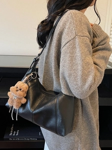 Minimalist black leather underarm bag with a cute plush bear charm for daily commute