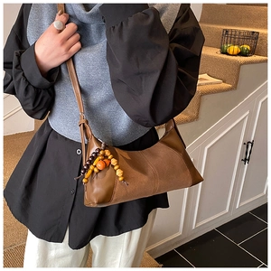Détail du sac sous l'aisselle vintage en cuir avec patchwork de daim et perles en bois