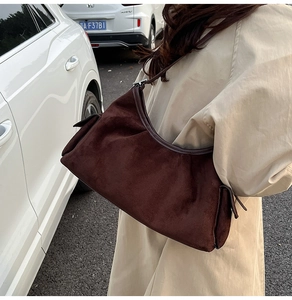 Détail du sac hobo en daim marron foncé avec plis et bandoulière en style de rue urbain
