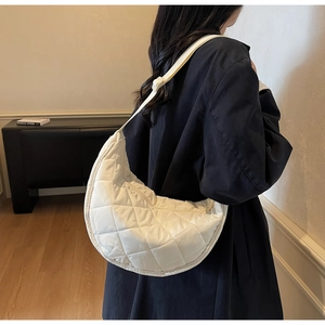 White quilted nylon hobo bag shown from the side with an adjustable shoulder strap