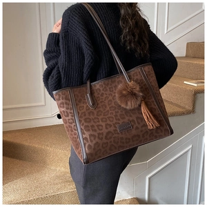 Detail of leopard print tote bag with plush ball charm and tassel on suede material