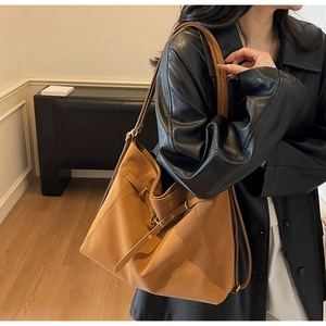 Detail view of large brown hobo bag featuring matte leather texture and gold buckles