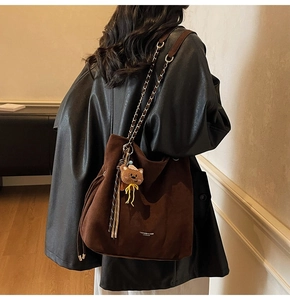 Détail du sac à bandoulière en daim marron foncé avec pendentif ours et chaîne