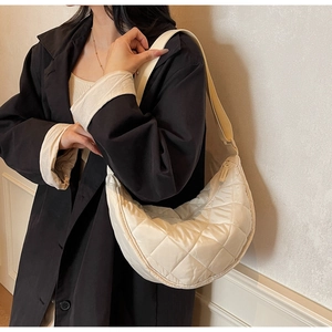 Close-up of quilted cream half-moon shoulder bag with wide strap and zip closure