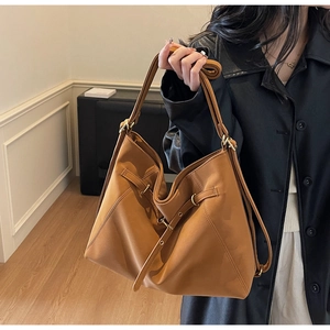 Detail of tan leather tote bag showing metallic buckle and minimalist slouchy Hobo design