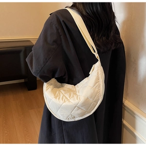 Detail of cream quilted crescent bag showing nylon diamond texture and wide strap
