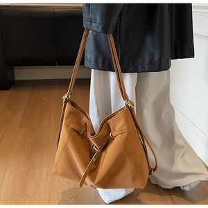 Close-up of large camel shoulder bag featuring adjustable straps and metal buckle details