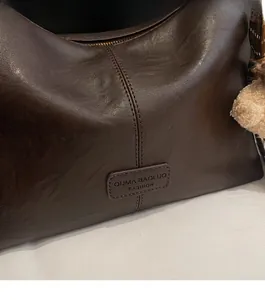 Close-up of vintage brown leather bag with stitch details and soft plush keychain