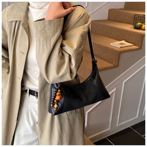 Détail du sac sous le bras noir vintage avec un ornement unique en perles de bois colorées