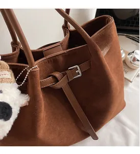 Dettaglio borsa tote in pelle scamosciata opaca con manici e finiture metalliche