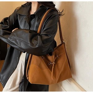 Detailed view of caramel leather tote bag featuring sleek straps and metal buckle accent