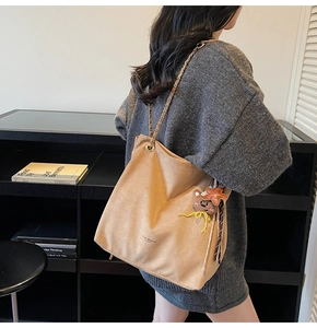 Détail d'un sac cabas en daim camel avec bandoulière chaîne et breloques en peluche