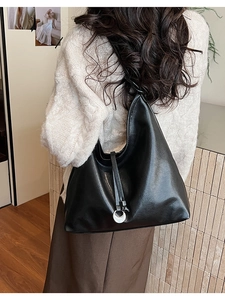 Detail of a large black minimalist hobo shoulder bag with a silver crescent pendant