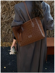 Detail of leopard print tote bag featuring faux suede texture and plush ball charm