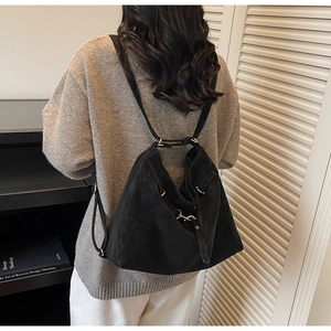 Detail of a black versatile crossbody bag with gold hardware and adjustable side straps
