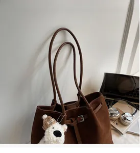 Dettaglio della borsa tote in pelle scamosciata marrone con fibbia e ciondolo a orsetto