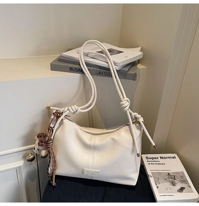 Detail of cream leather shoulder bag with rope strap and cute plush puppy charm