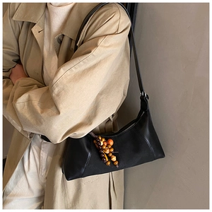 Gros plan du sac baguette en cuir noir avec breloques vintage en perles de bois colorées