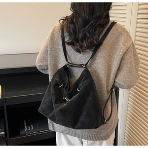 Detail view of large matte black hobo bag with gold buckle on a slim shoulder strap