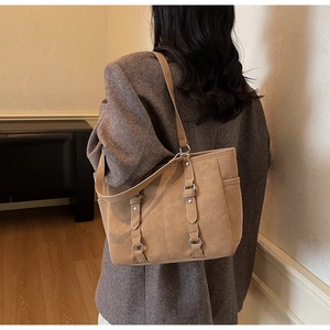 Detail of light brown tote bag with suede texture and silver buckle on model
