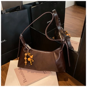Détail du sac bandoulière en cuir et daim marron avec pendentif en perles de bois unique