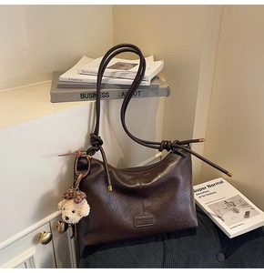 Detail of vintage brown tote bag with leather texture and cute plush puppy keychain