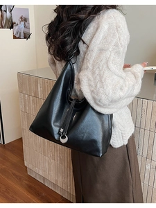 Lifestyle view of a large black matte leather hobo bag worn by a model in a minimal setting