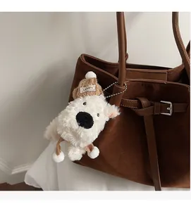 Dettaglio di un charm per borsa in peluche bianco con berretto marrone in maglia
