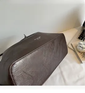 Detail of vintage pleated brown leather tote bag with silver logo in an office setting