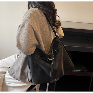 Detail of black large capacity hobo bag featuring premium matte leather and golden buckle