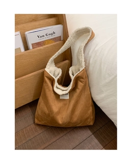 Detail of brown suede tote bag featuring white faux shearling trim and broad shoulder strap