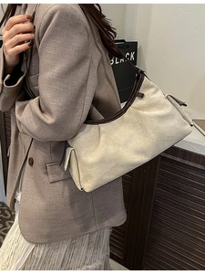 Sac hobo chic en toile beige avec bordure en cuir marron porté à l'épaule pour un style décontracté