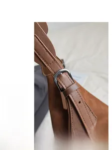 Close-up of brown suede leather texture and metallic pin buckle with neat stitching details