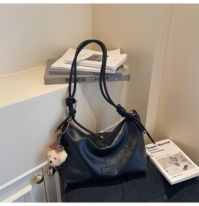 Detail of black vintage shoulder bag with luxury leather texture and cute bear charm