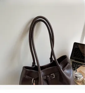 Detail of dark brown leather tote with soft pleated texture and durable shoulder handle