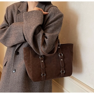 Detail of vintage brown tote bag with decorative metal ring straps on wool coat