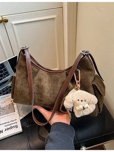 Sac fourre-tout marron en cuir suédé avec porte-clé chien peluche dans un cadre bureau